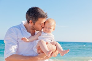 dad kissing baby on beach